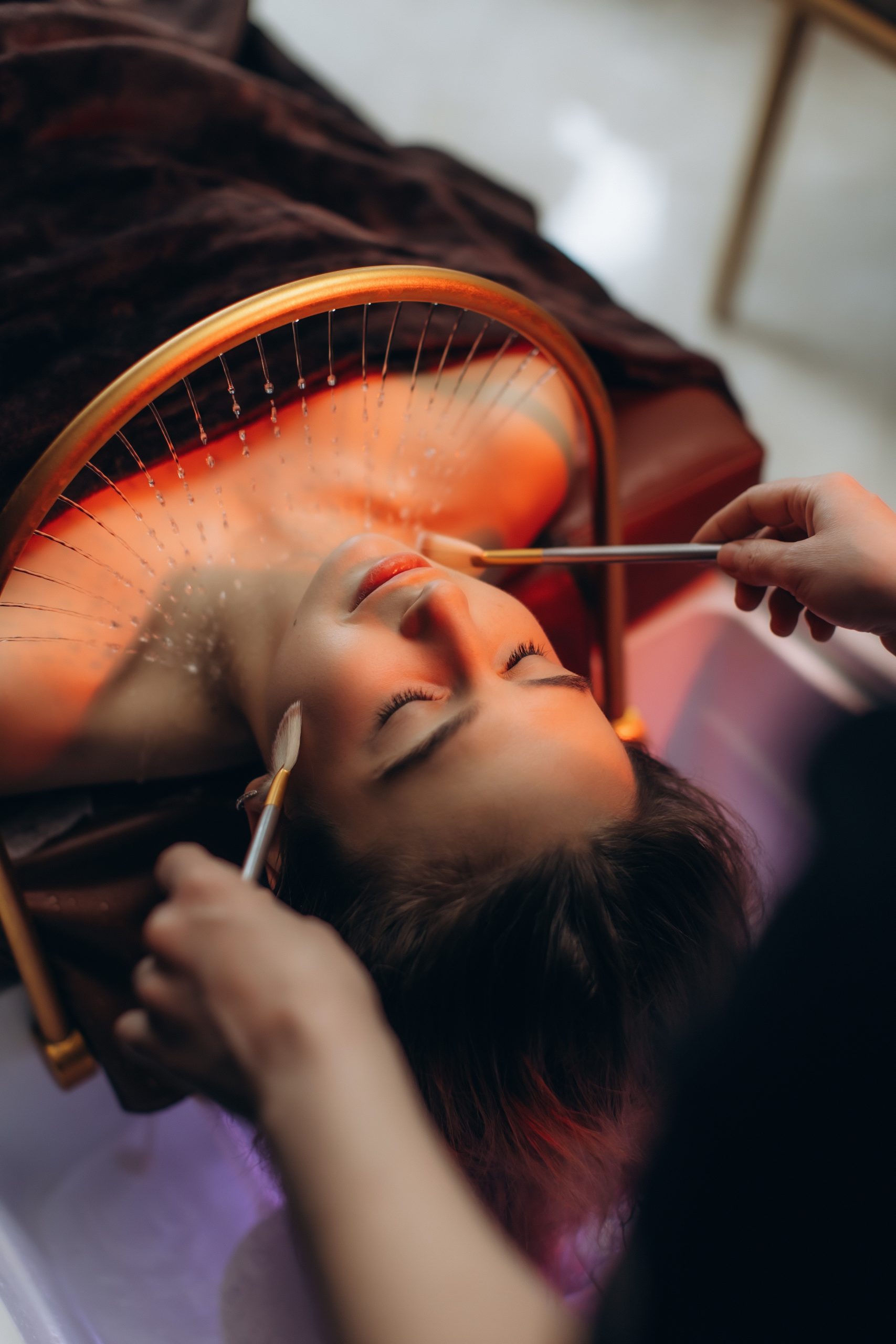 Young woman lying back receiving a rejuvenating water therapy facial with brushes at a wellness spa salon for beauty and relaxation